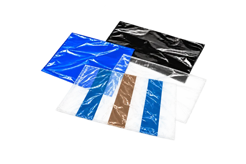 Dünne blaue und schwarze Folienproben, eine klare Probe und ein klarer flacher Beutel mit neutralen geometrischen Streifen in Blau und Warmgrau/Braun.