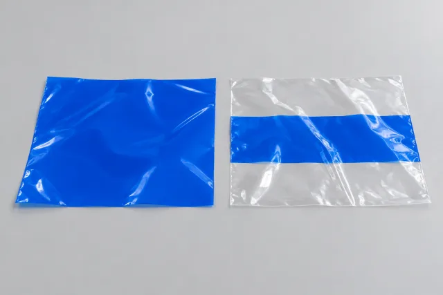 Links ein vollständig blaues Folienmuster, rechts eine transparente Folienprobe mit einem begrenzten blauen Druckstreifen.